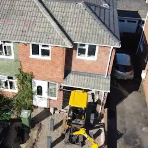 Extension footprint being dug out beside a semi-detached house with a mini digger