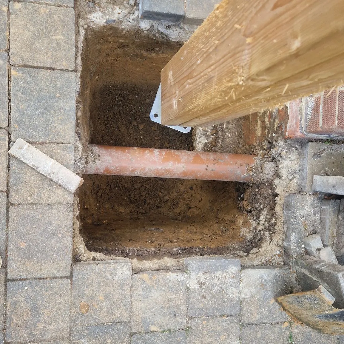 Excavated trench with a drainage pipe beneath a timber lintel